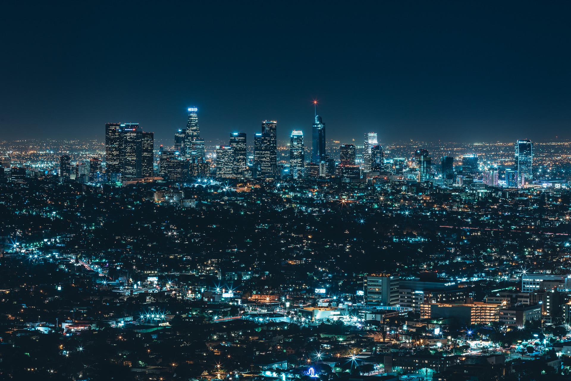 Image of an entire city lit up at night - the lights are a bluey colour. 