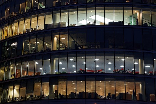 Outside view of a building with 4 floors. 3 floors have lights on.